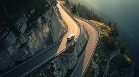Vue aérienne d'une route de montagne sinueuse avec un véhicule négociant un virage serré