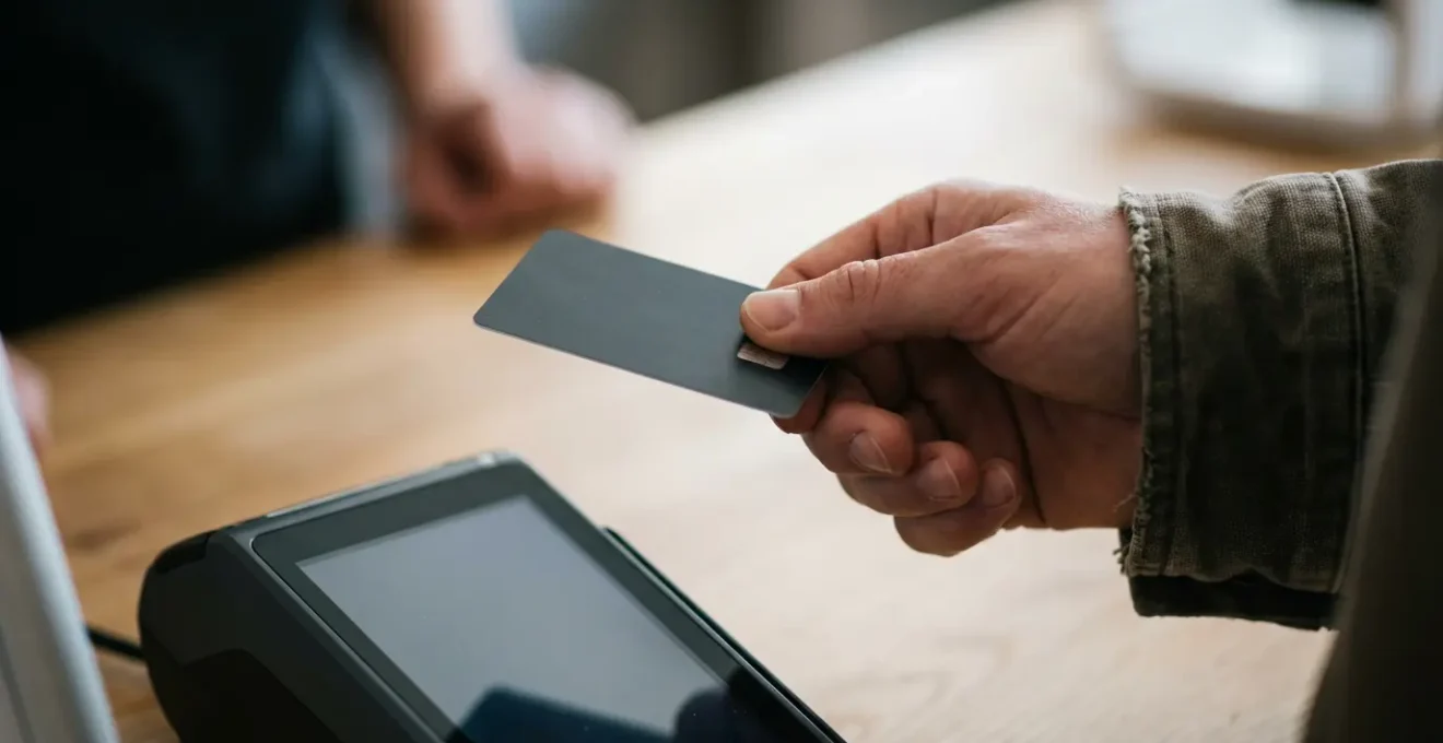 Main tenant une carte bancaire près d'un terminal de paiement dans une agence de location