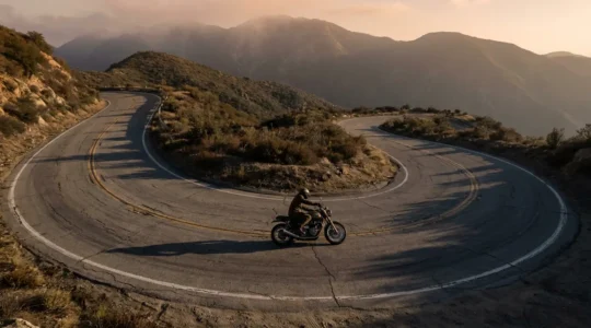 Motard négociant une épingle à cheveux en montagne avec inclinaison marquée et technique de contre-braquage